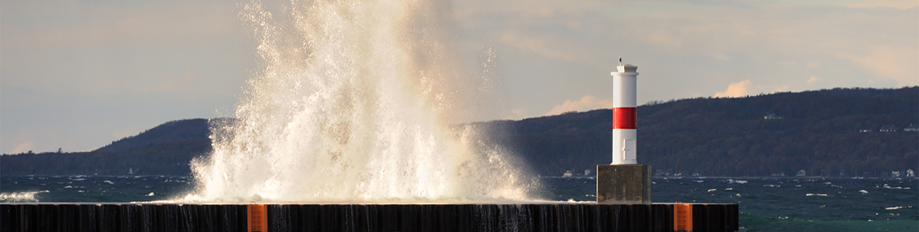 Water crashing over a dock with hillside in the background.